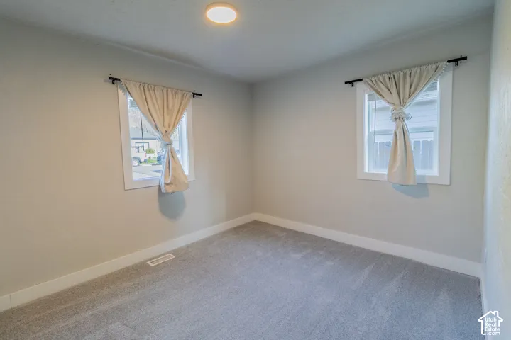 Recessed ceiling light, two windows with white trim, light gray walls, and gray carpet flooring