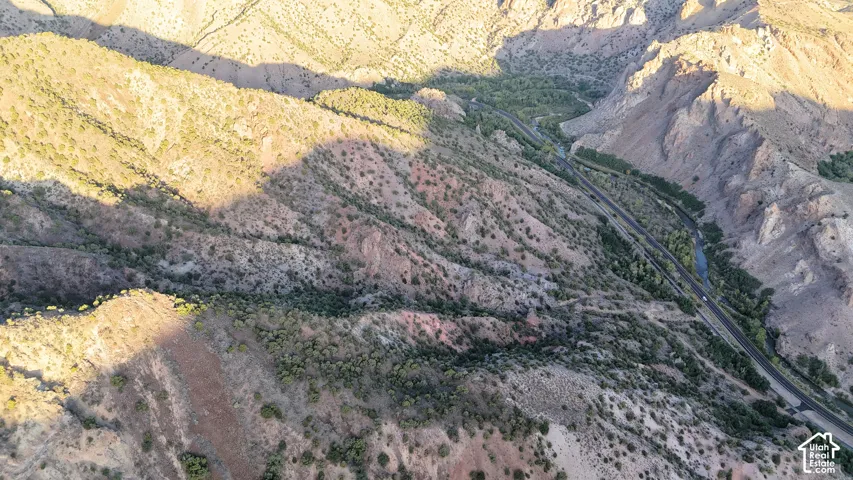 Rugged mountain terrain, winding highway, river, and verdant riparian areas