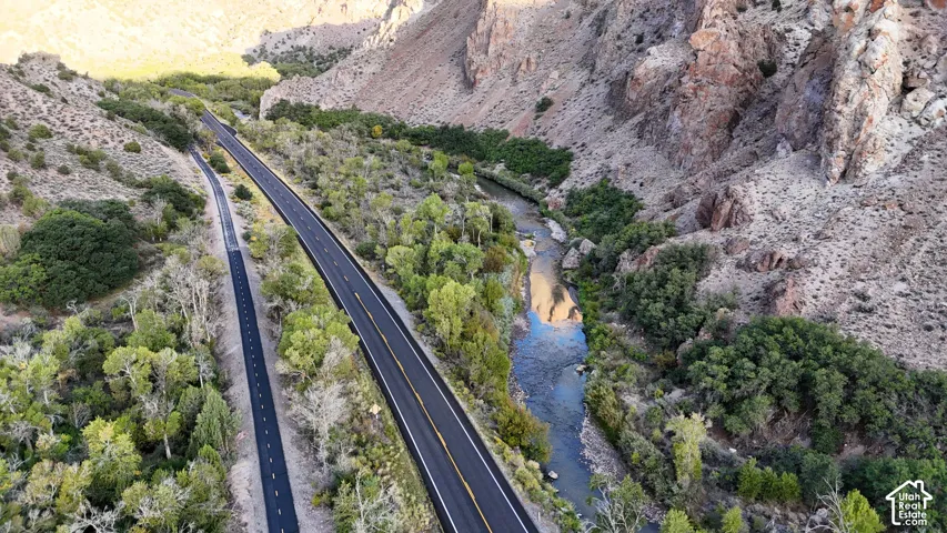 Winding roads traversing a canyon landscape with a flowing river and abundant mature trees