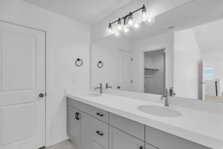 Primary bath with dual sinks, painted wood cabinets and quartz slab countertops.