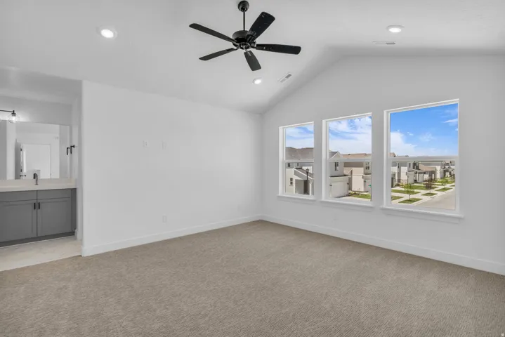 Primary bedroom with vaulted ceiling, ceiling fans and terrific windows.