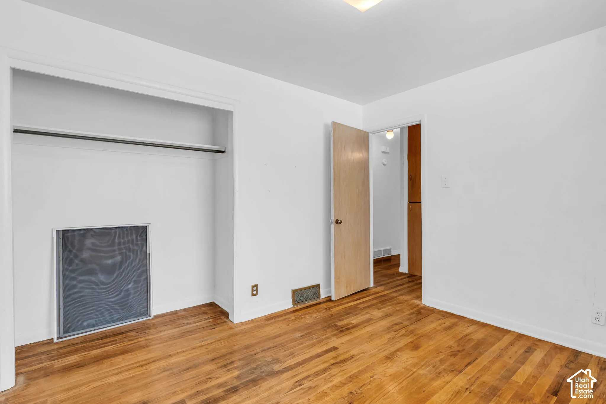 Hardwood flooring throughout, white painted walls, and an open doorway