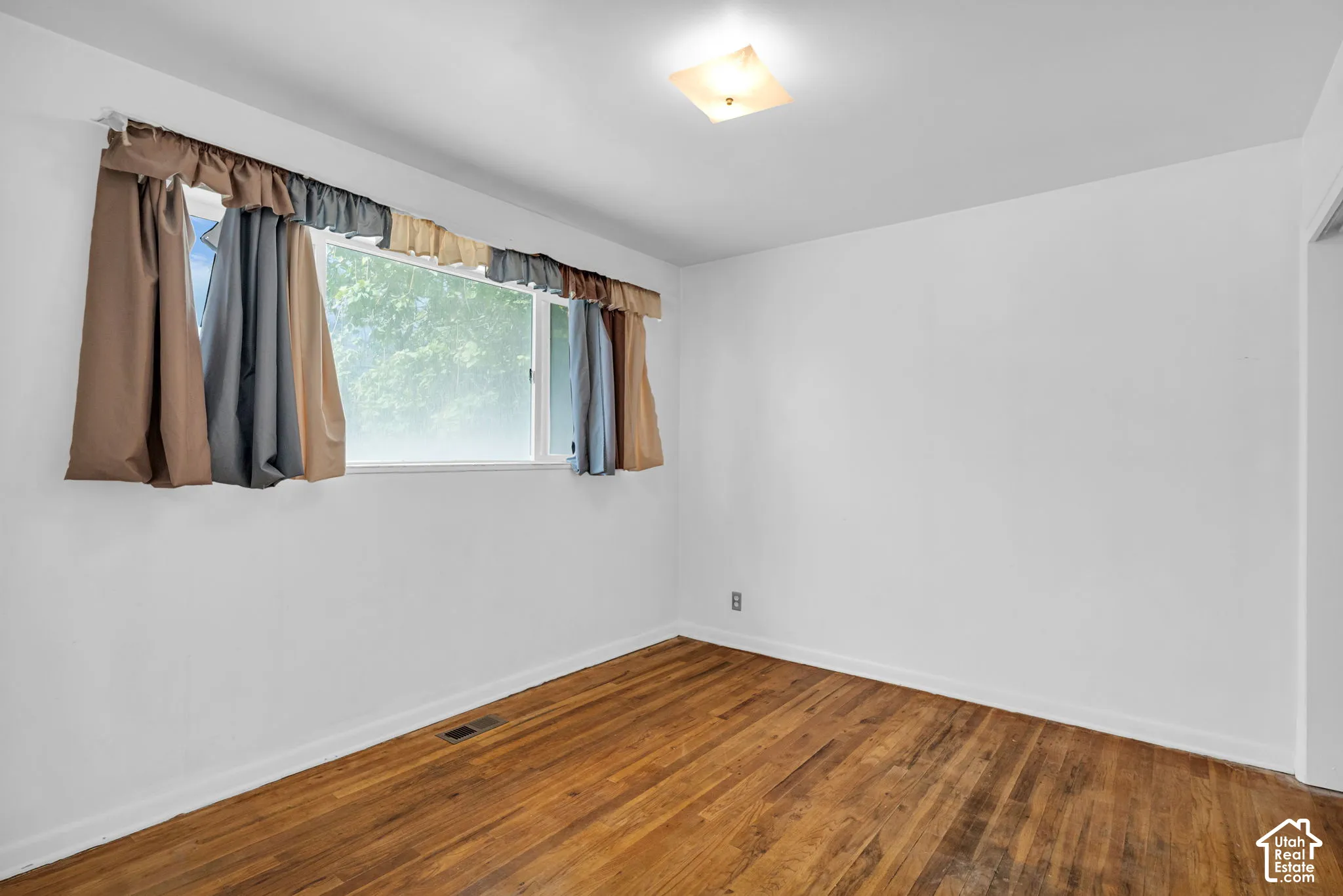 Hardwood flooring with a matte finish, white painted walls, and a ceiling-mounted light fixture