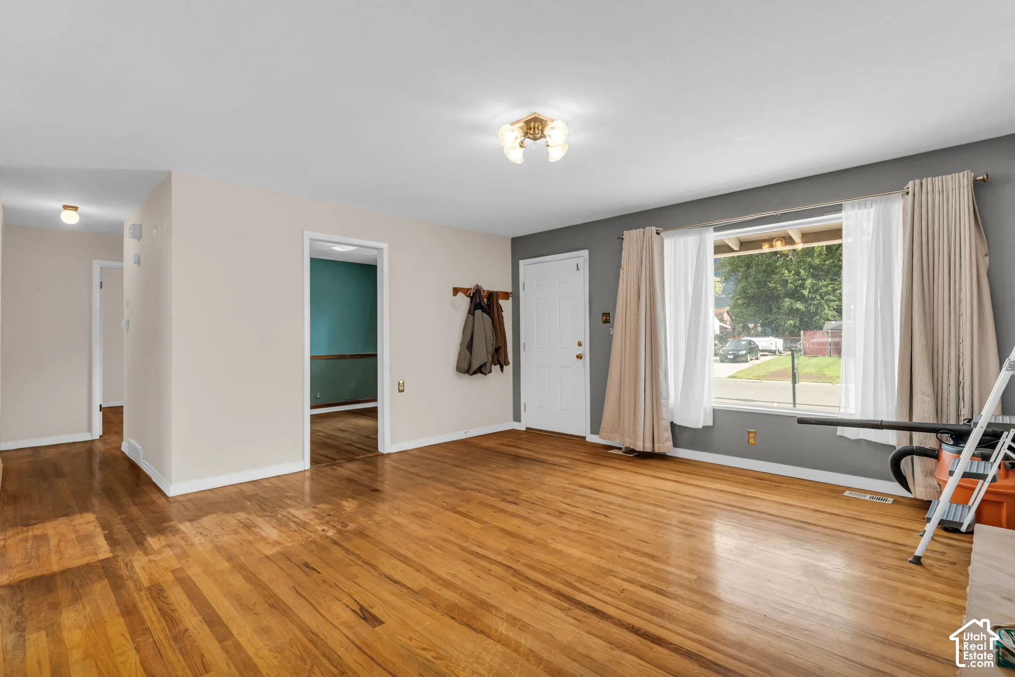 Hardwood flooring throughout, a large front window, and a coat rack by the entry door
