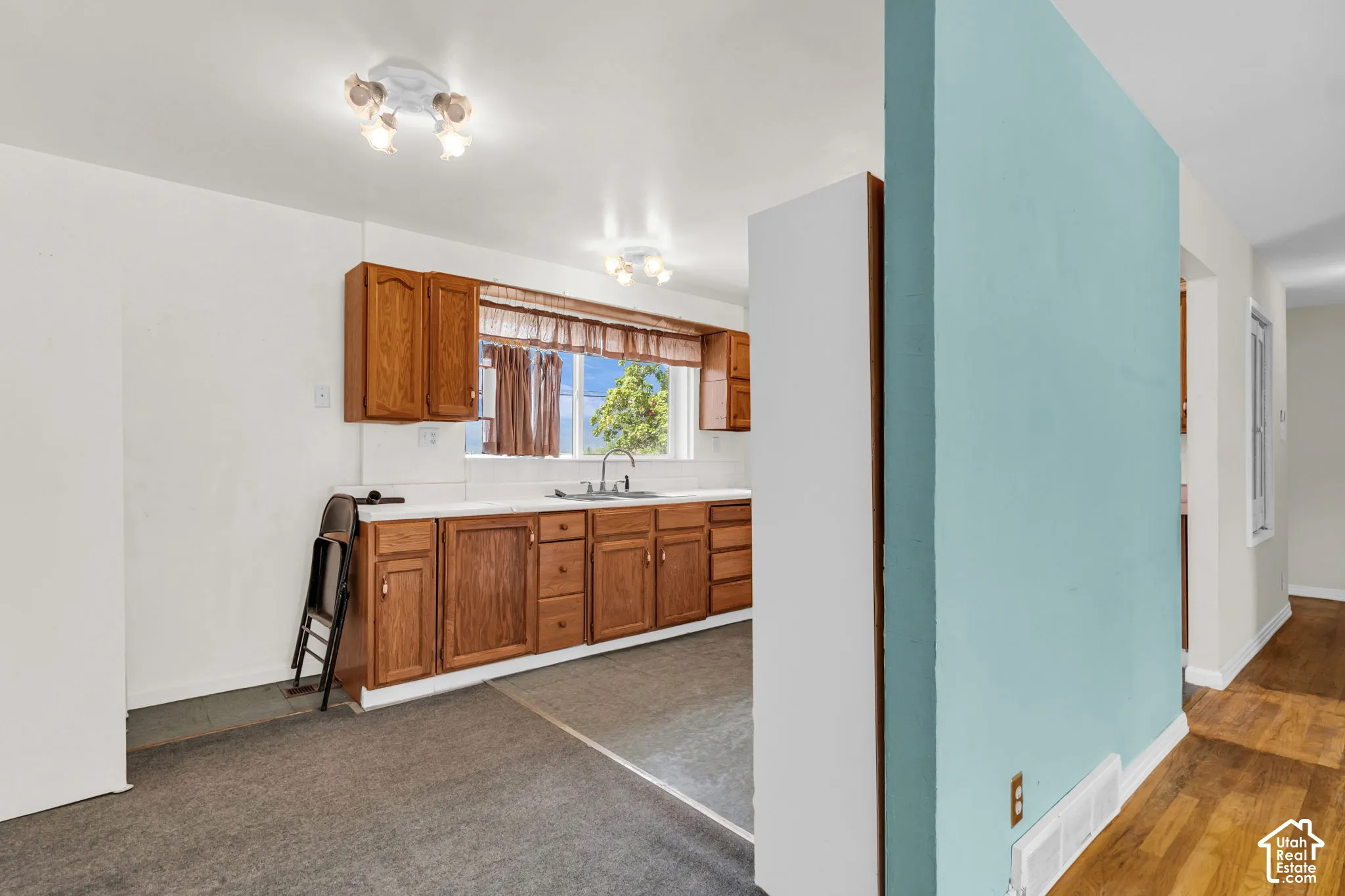 Kitchen with wood cabinetry, white countertops, and a stainless steel sink