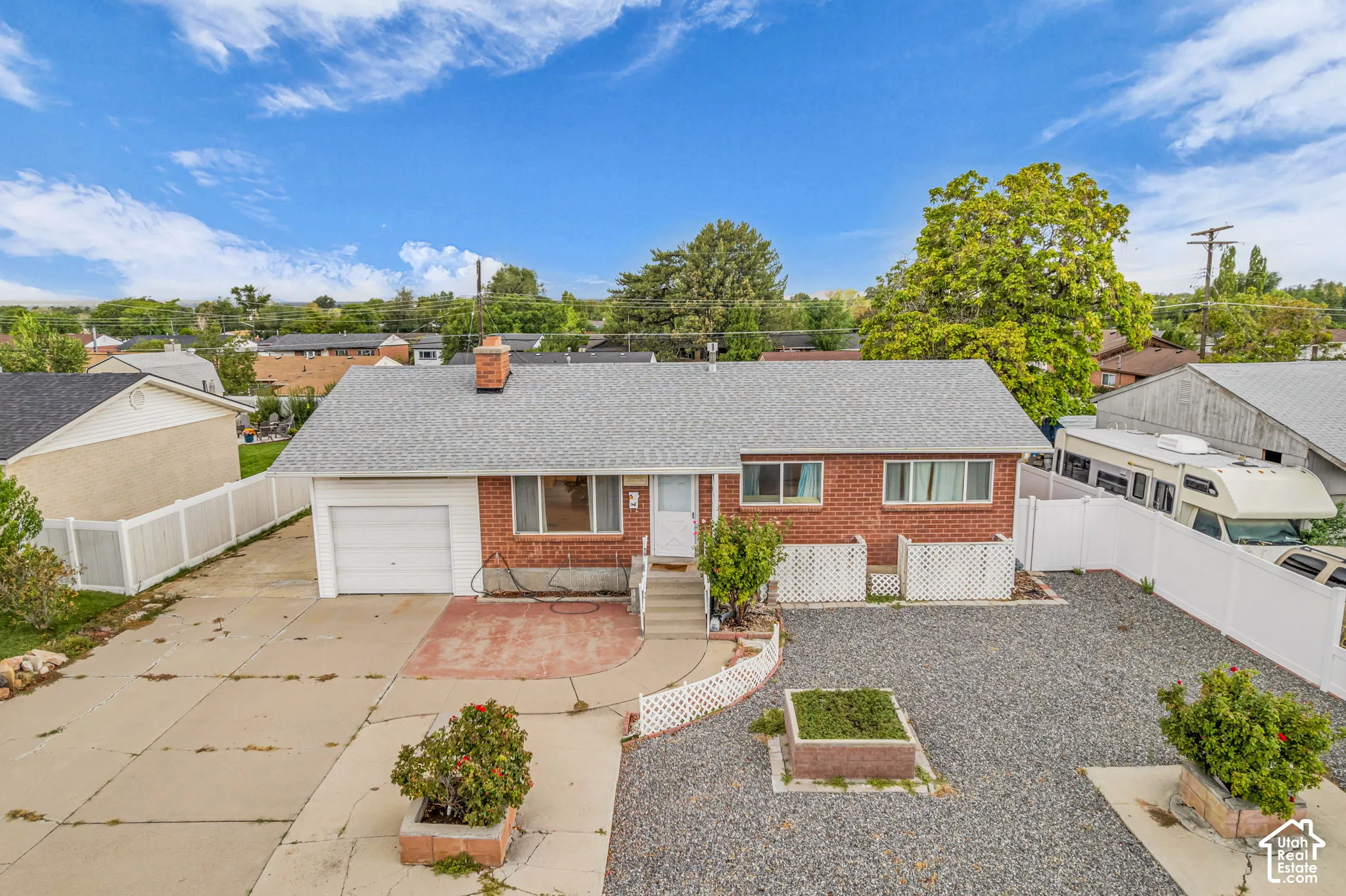 Brick exterior with a white vinyl fence and attached garage