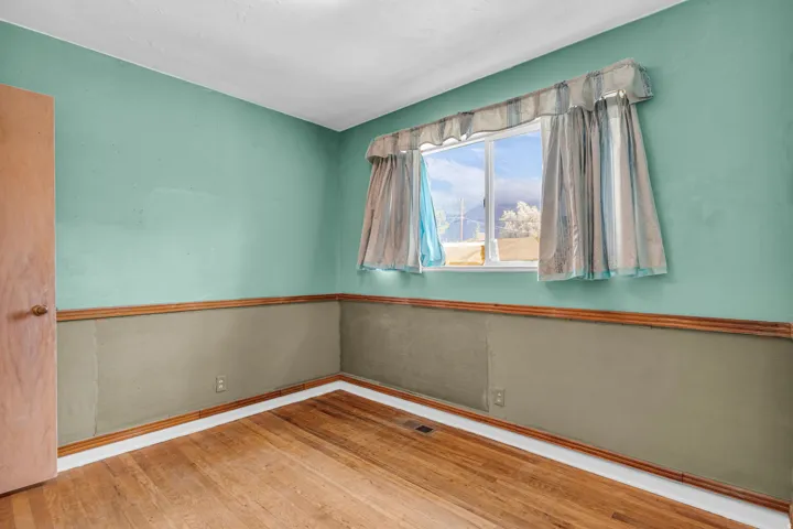 Wood-finish flooring, wood trim, and a window with natural light