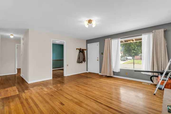 Hardwood flooring throughout, a large front window, and a coat rack by the entry door