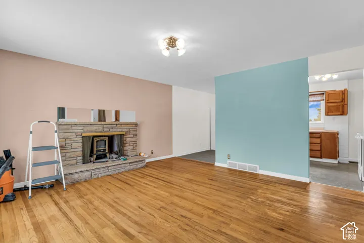 Stone-clad fireplace with wood-burning insert, wood flooring, and recessed lighting