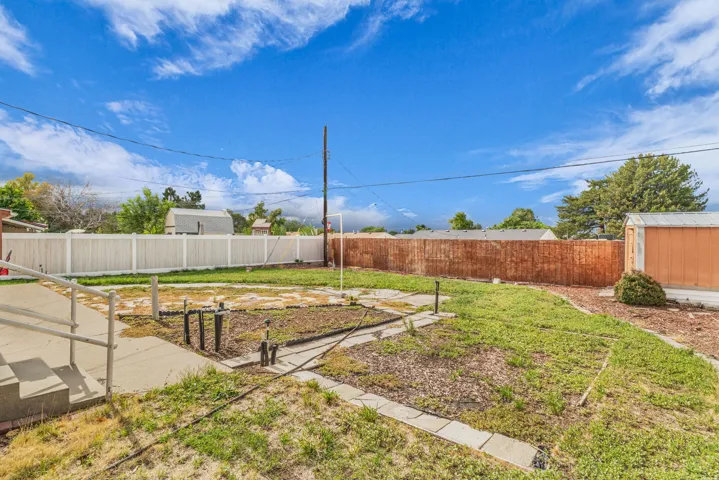 Expansive backyard space featuring concrete pathways and a storage shed