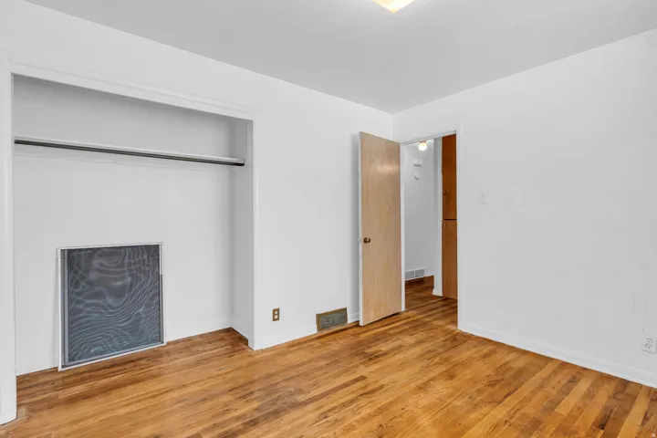 Hardwood flooring throughout, white painted walls, and an open doorway