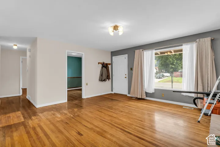 Hardwood flooring throughout, a large front window, and a coat rack by the entry door