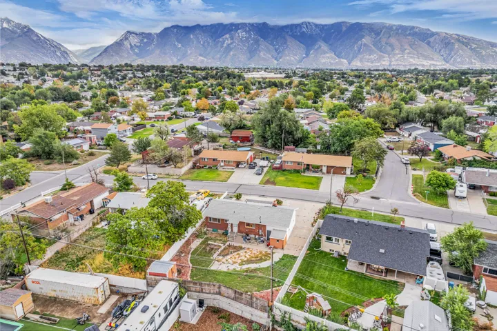 Residential neighborhood with mature trees, mountain backdrop, and paved streets