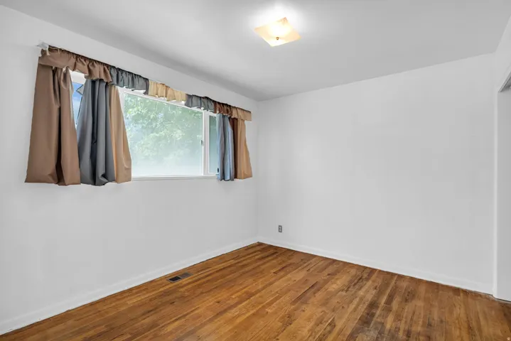 Hardwood flooring with a matte finish, white painted walls, and a ceiling-mounted light fixture
