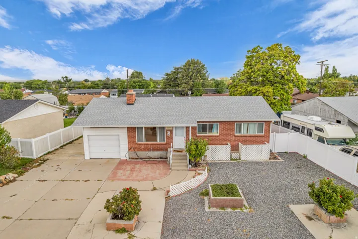 Brick exterior with a white vinyl fence and attached garage