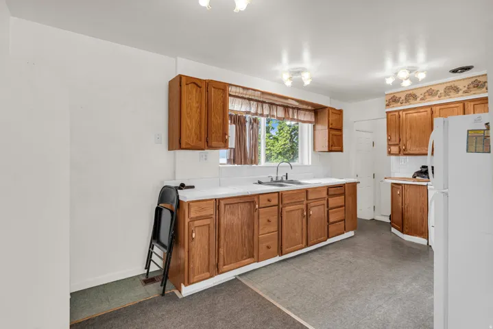 Kitchen featuring wood cabinetry, white countertops, a double-basin sink, and white tile backsplash