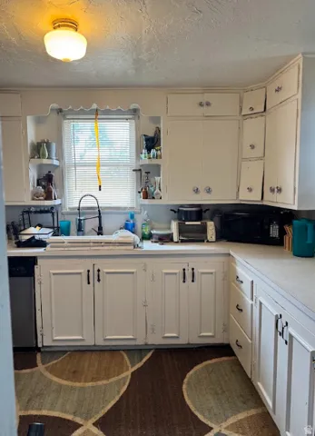 White cabinetry with contrasting hardware, light-toned countertops, and a built-in dishwasher