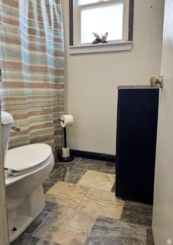 Tiled flooring with varied rectangular patterns, white window trim, and a dark vanity with a textured countertop