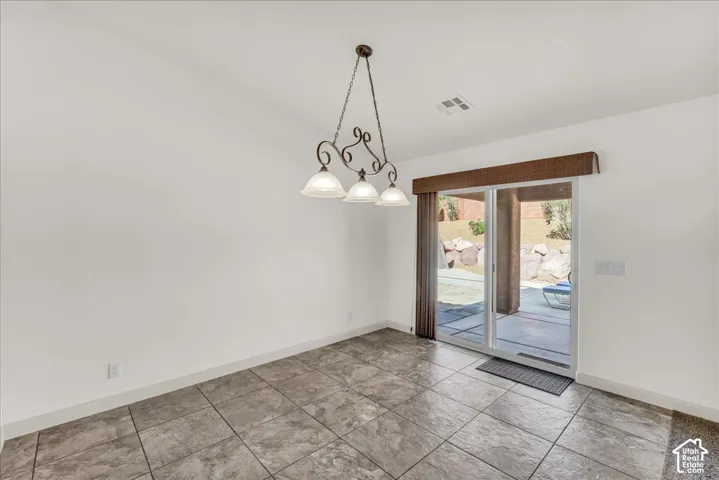 Tile flooring, sliding glass door, overhead lighting fixture, covered patio, rock landscaping