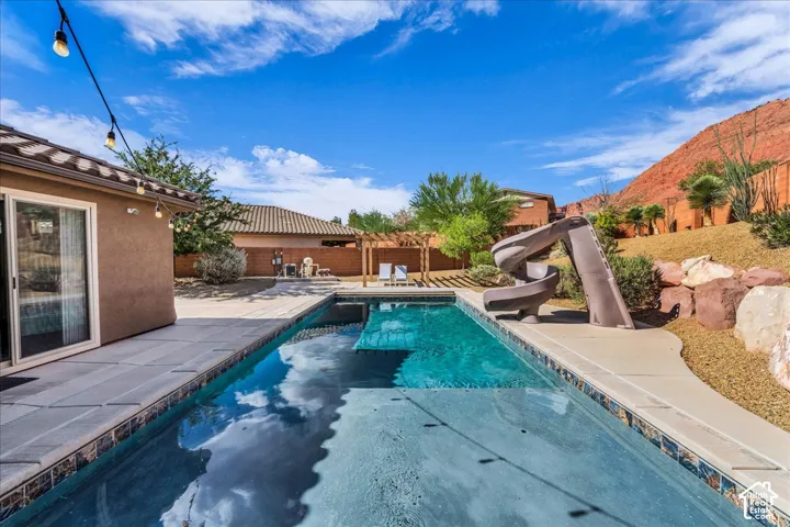 Outdoor swimming pool featuring a curved slide and a sun ledge