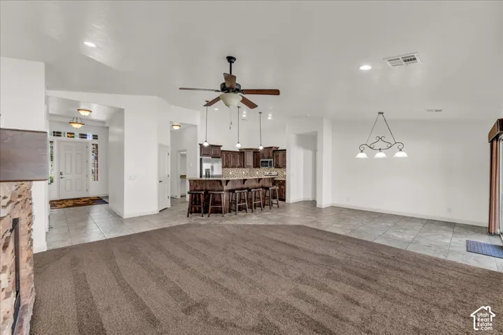 Spacious interior featuring a stone-clad fireplace, ceiling fan with integrated lighting, recessed ceiling lighting, and tile flooring