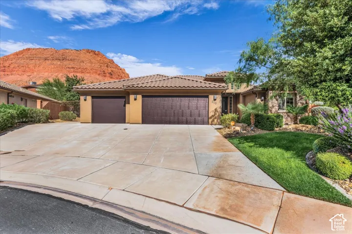 Striking Southwestern residence showcasing a dual-bay garage with dark wood-finish doors, expansive concrete driveway with clean geometric scoring, and warm terracotta stucco exterior