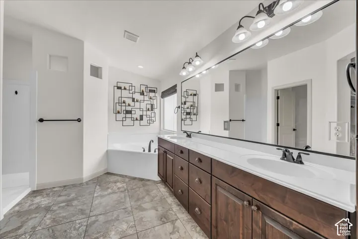 Dual vanity with integrated sinks, dark wood-finish cabinetry, and a large wall-mounted mirror