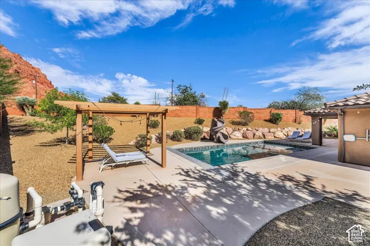 Paved patio with a rectangular swimming pool, integrated spa, and an attached pergola