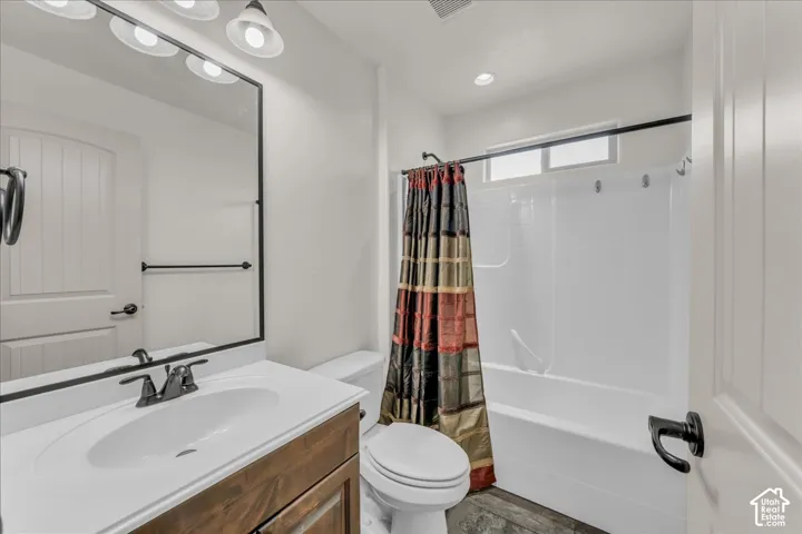 Bathroom featuring a wood-finish vanity with a white countertop, an undermount sink, and a black-framed mirror