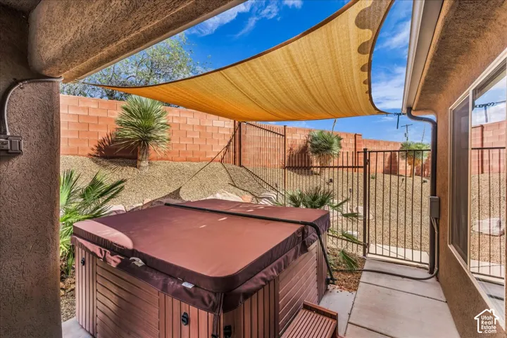 Covered patio featuring a spa, a shade sail, and a block fence