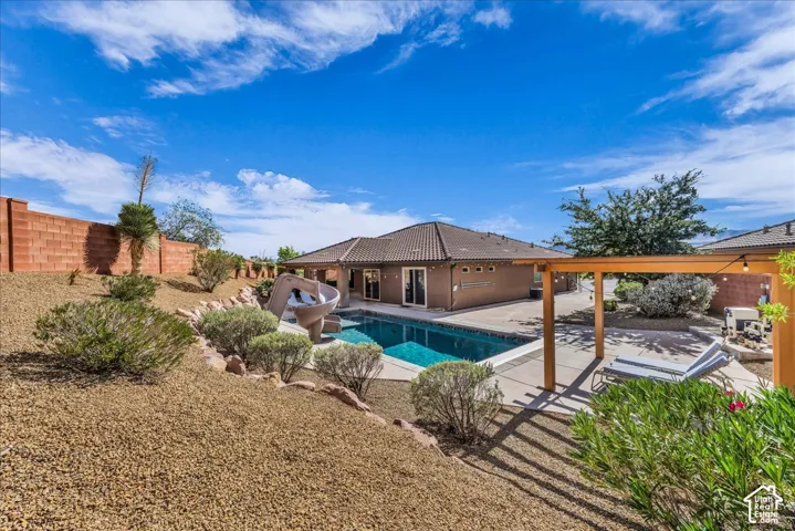 Expansive backyard oasis featuring a resort-style swimming pool with surrounding hardscape, mature landscaping with native desert vegetation, wood-beam pergola structure, and multiple lounge areas