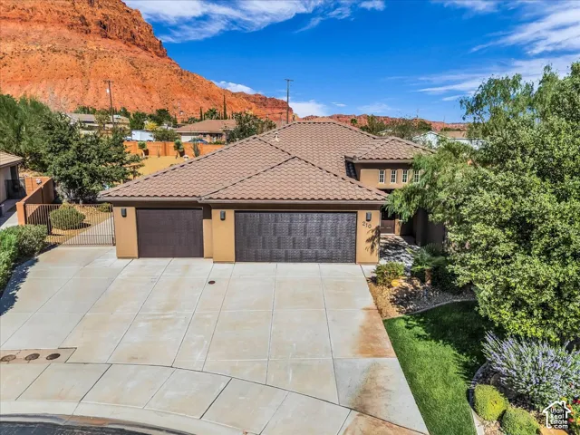 Two-car garage with textured doors, stucco exterior, tiled roof, and paved driveway