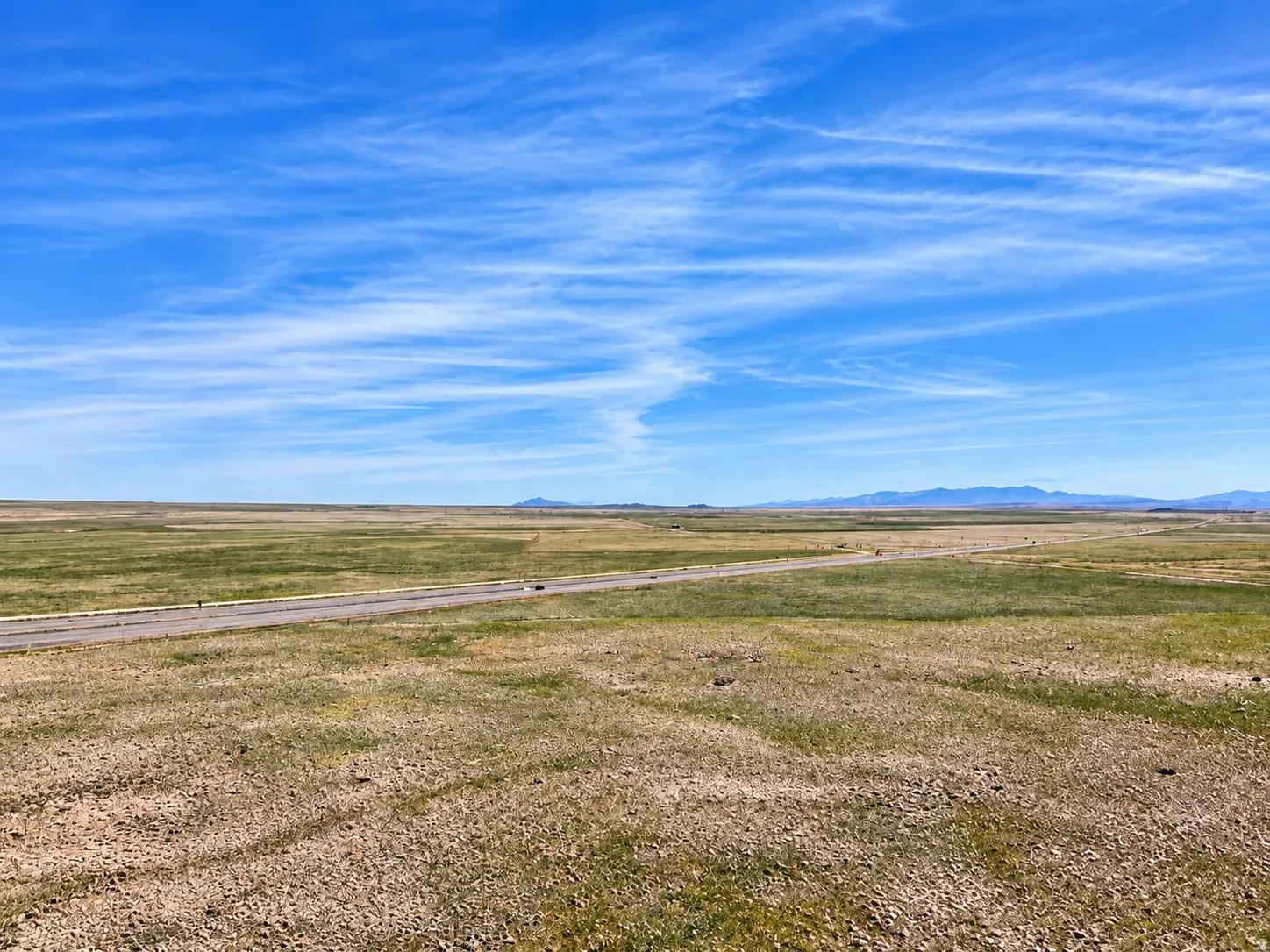 Expansive open land featuring a paved road and distant mountains