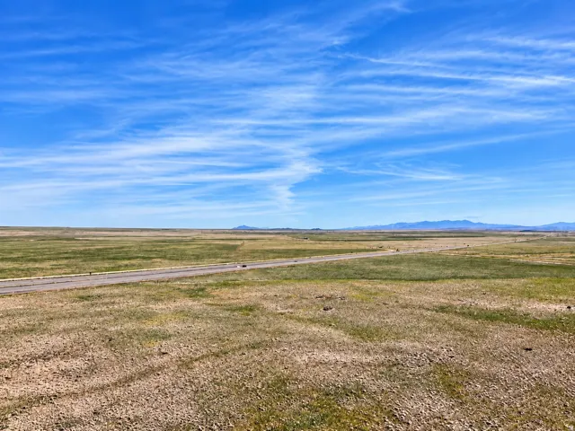Expansive open land featuring a paved road and distant mountains