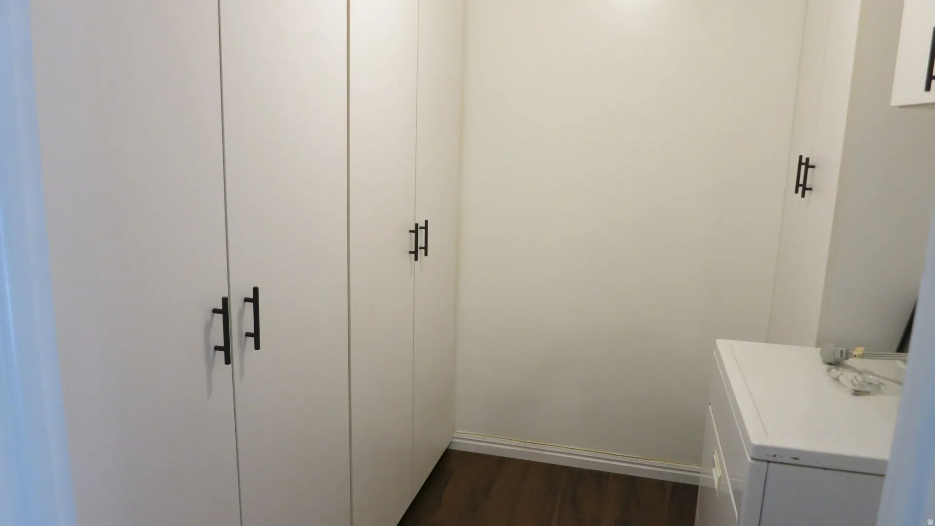 Built-in white cabinetry with matte black hardware and wood-finish flooring