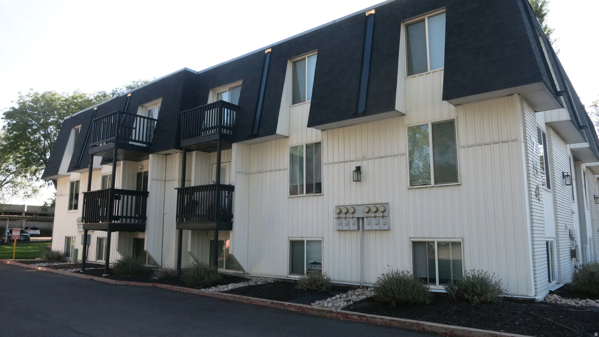 Multi-story building with a dark shingle roof and white vertical siding