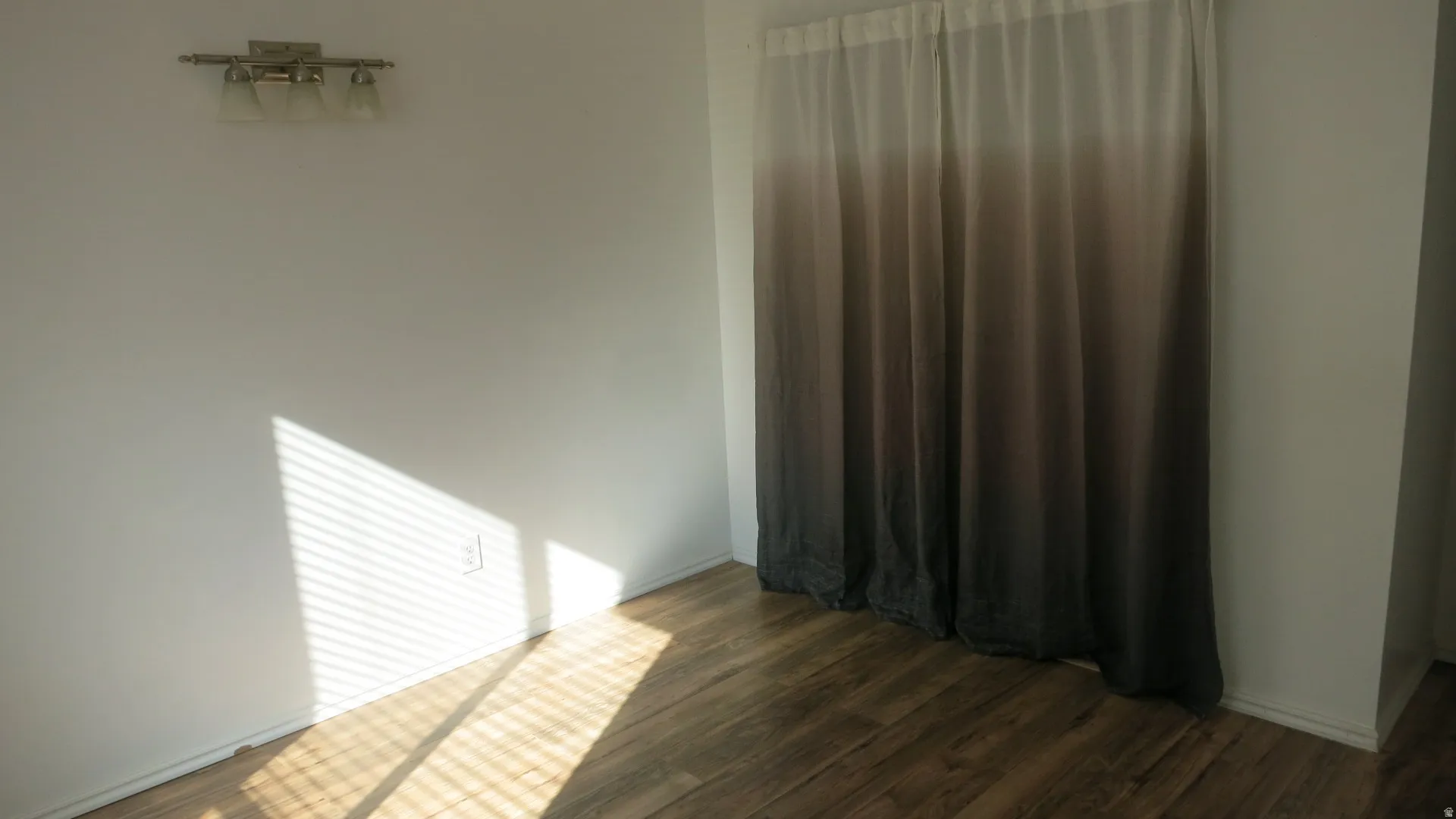 Bedroom 2 - Wood-finish flooring with white walls and a three-light vanity fixture