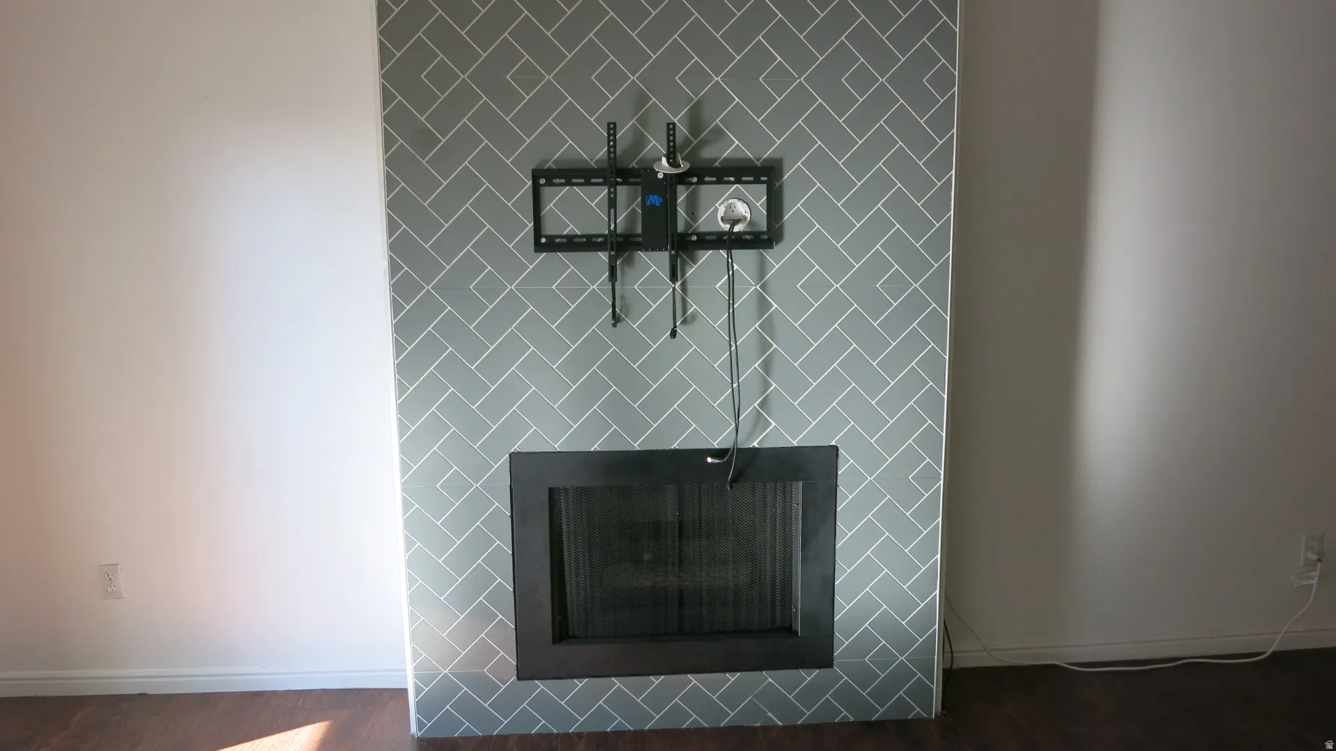Fireplace with herringbone tile surround, dark wood-finish flooring
