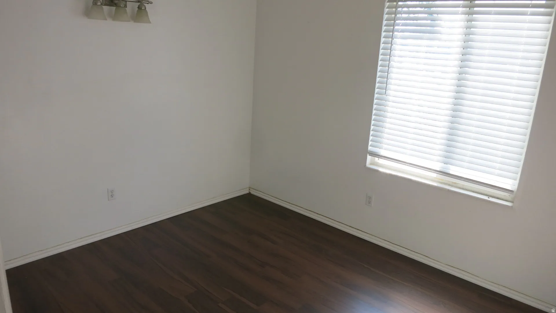 Bedroom 1 - Wood-finish flooring, white walls, and a window with horizontal blinds
