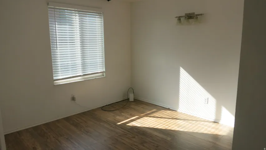 Bedroom 2 - Wood-finish flooring, white horizontal blinds, and a wall-mounted light fixture