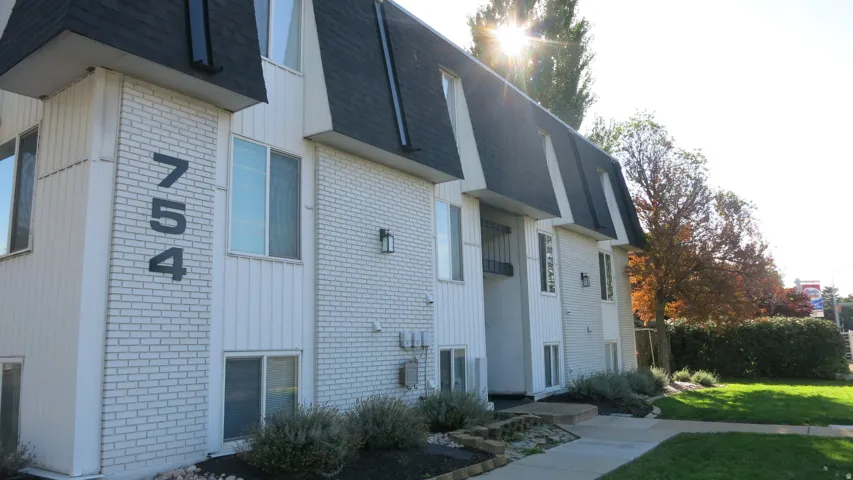 White brick and vertical siding exterior with dark mansard roofing