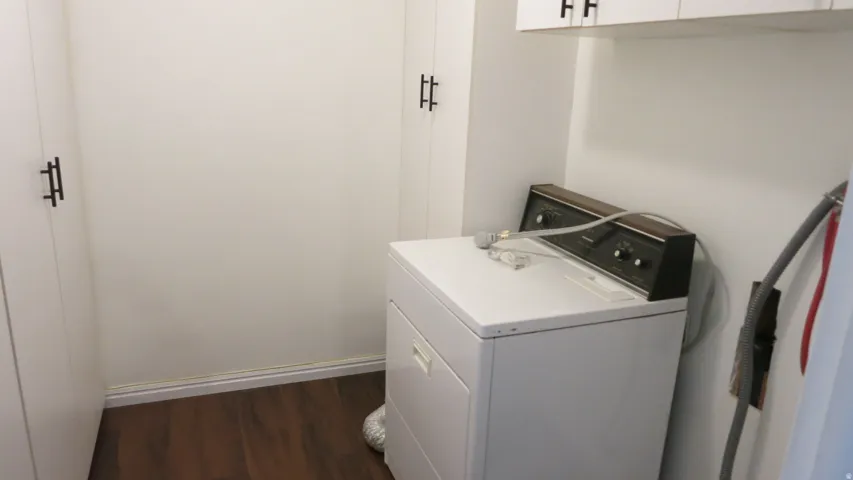Built-in cabinetry with black hardware, wood-finish flooring, and overhead cabinetry