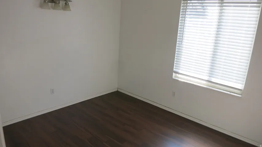 Bedroom 1 - Wood-finish flooring, white walls, and a window with horizontal blinds