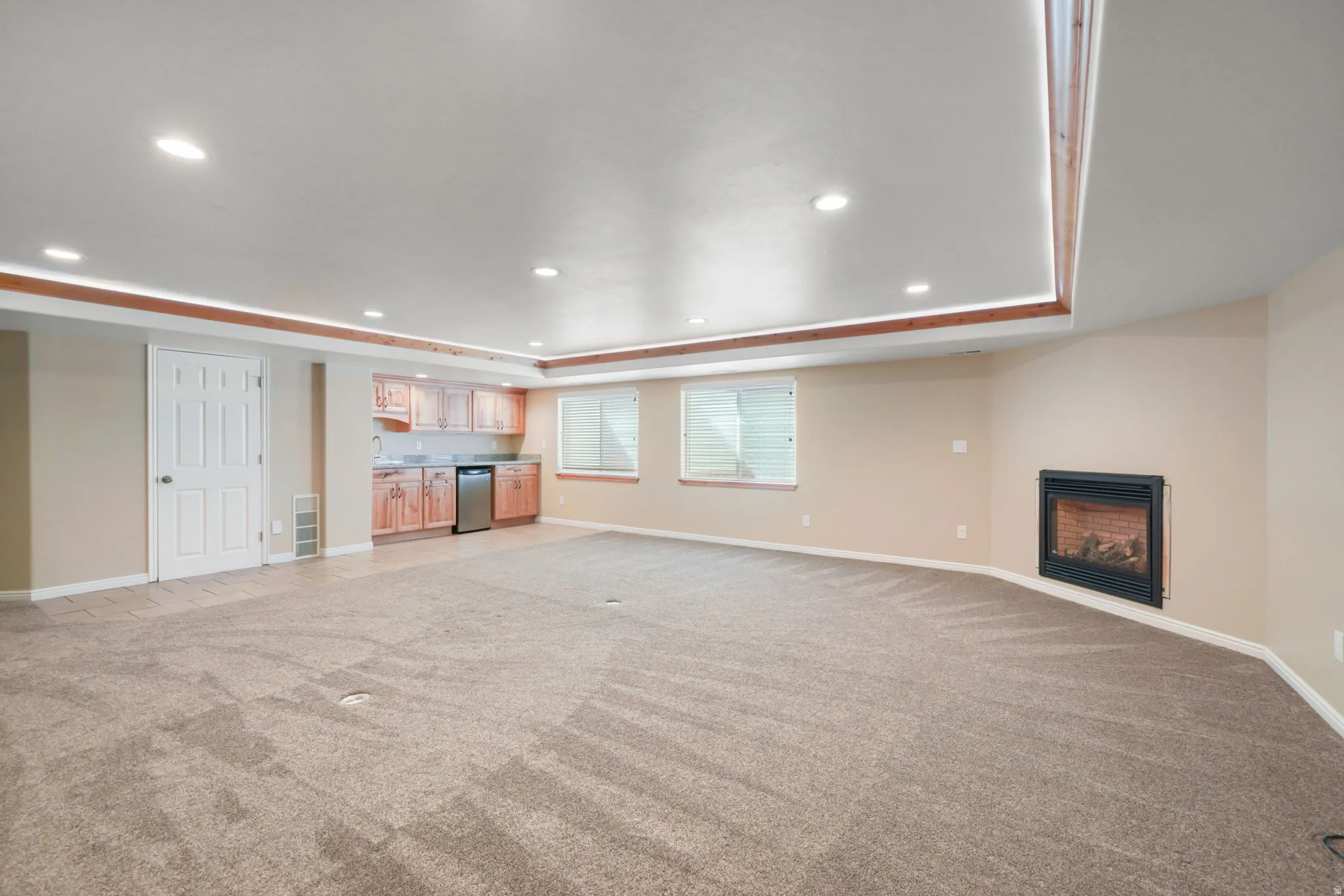 Spacious room featuring neutral carpeting, recessed lighting, and a built-in fireplace