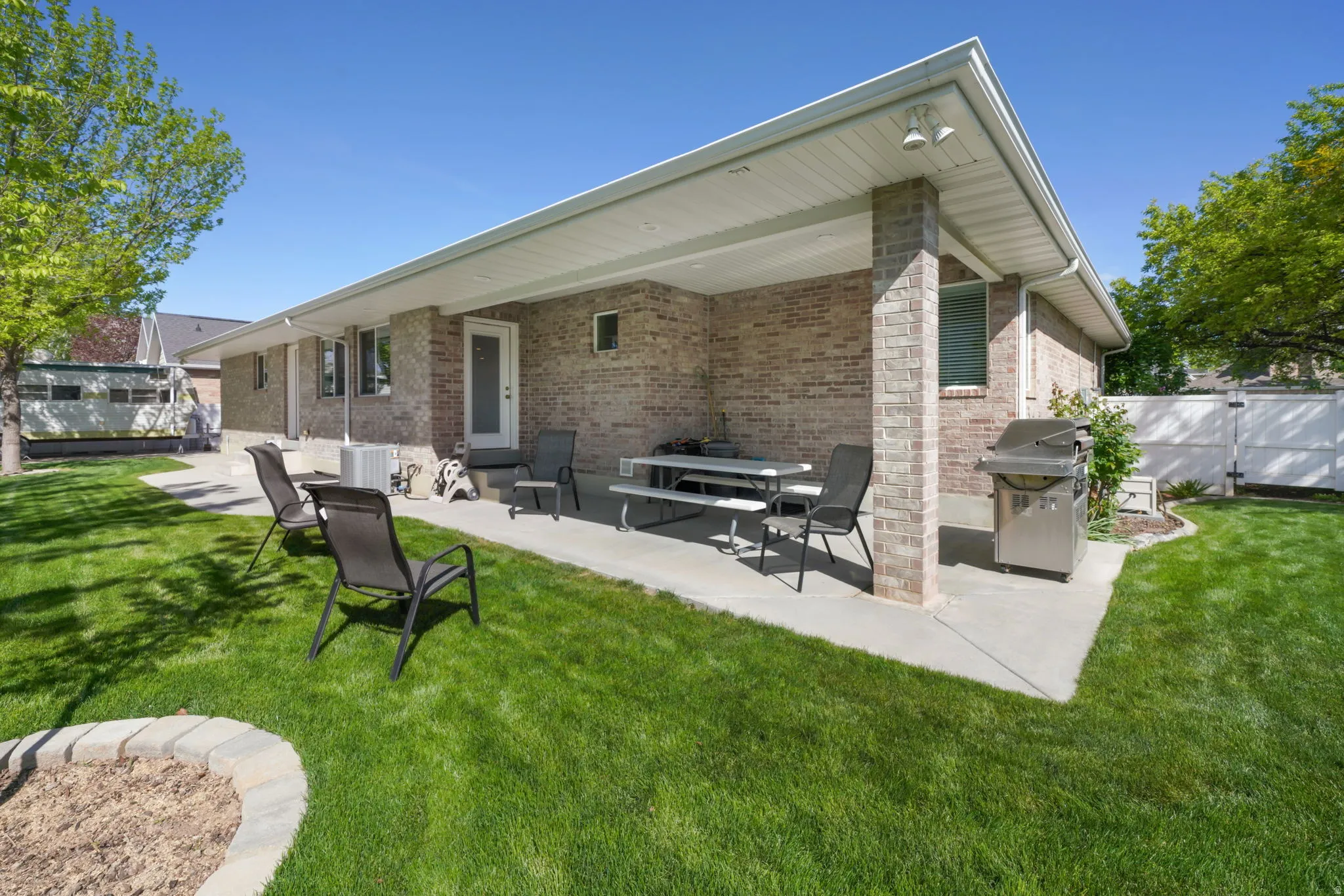 Brick exterior featuring a covered patio with recessed lighting, concrete flooring, and a verdant lawn