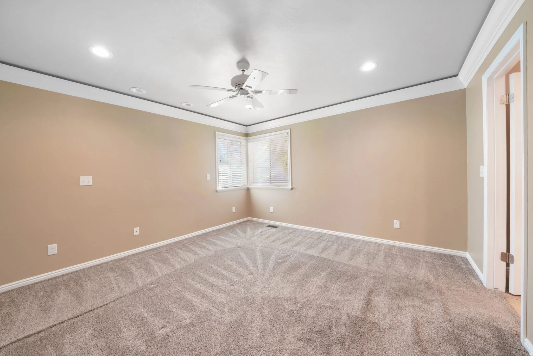 Recessed lighting, crown molding, corner windows with blinds, ceiling fan, and carpeted flooring