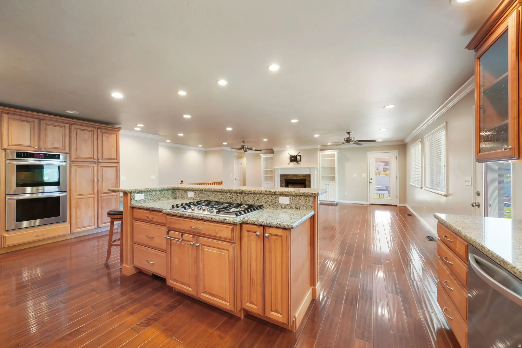 Hardwood-finish flooring, recessed lighting, built-in double ovens, and a kitchen island with cooktop and granite countertops