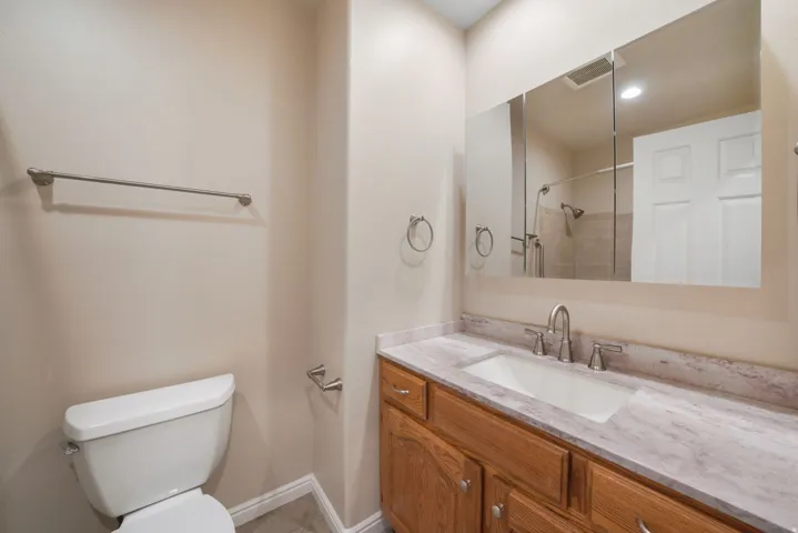 Vanity with wood-finish cabinetry, integrated sink, brushed nickel faucet, and a large mirrored medicine cabinet