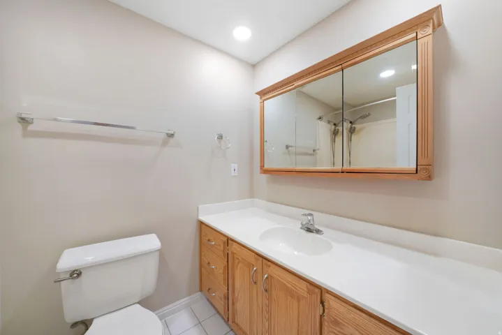 Wood-finish vanity with white countertop, integrated sink, and chrome faucet