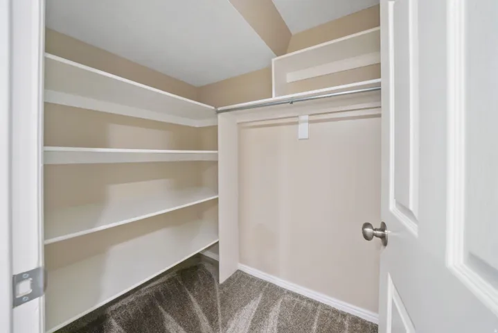 Integrated shelving system with white finishes, chrome hanging rod, and neutral-toned wall paint